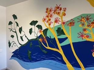A painted mural on a wall at Chebsey ward showing green ivy and a yellow plant with red flowers.