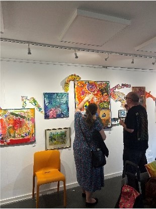 A woman and a man looking and talking about artwork on display at the exhibition.