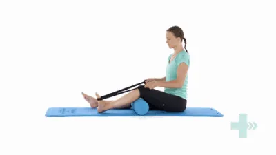 A moving image of a person sitting on the floor with a foam roller under their knee. A rubber band is looped around the foot and is being pulled back.