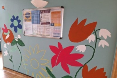 A mural of flowers painted on a wall around a noticeboard at Chebsey ward
