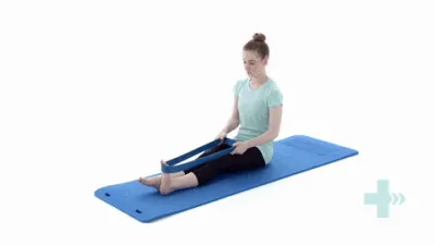 A moving image of a person sat on the floor with legs out straight infront of them. A rubber band is being held around one foot and is being pulled back by their hands.