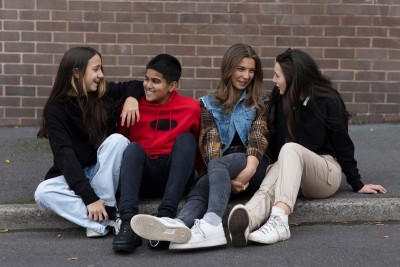 Four young people sit on the floor, talking.